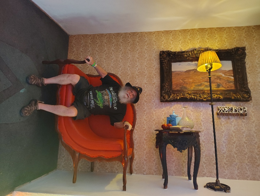 Photo of OZ in an Optical Illusion seat at X3NS3S (Xenses). The photo makes it appear as if OZ is sitting on the wall, rather than the floor.